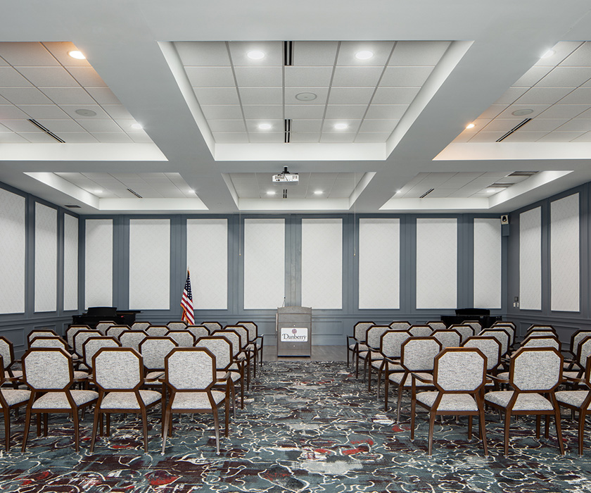 Meeting room with rows of empty chairs and a podium in a senior living community.
