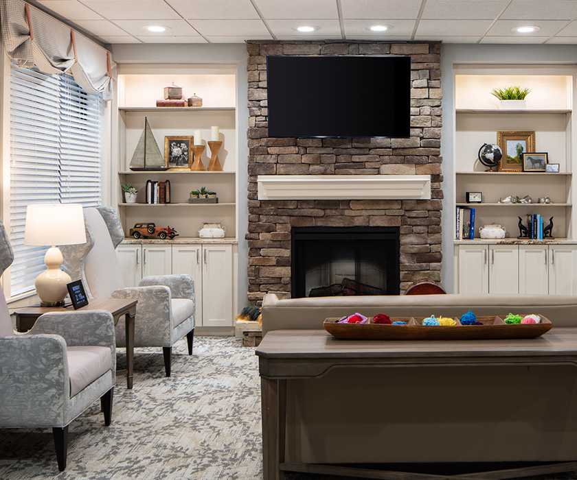 Cozy living area with stone fireplace and bookshelves in a senior living unit.