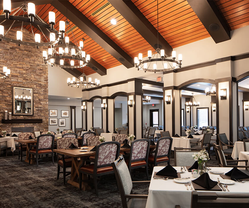 Elegant dining area with vaulted ceiling and chandeliers in a senior living community.