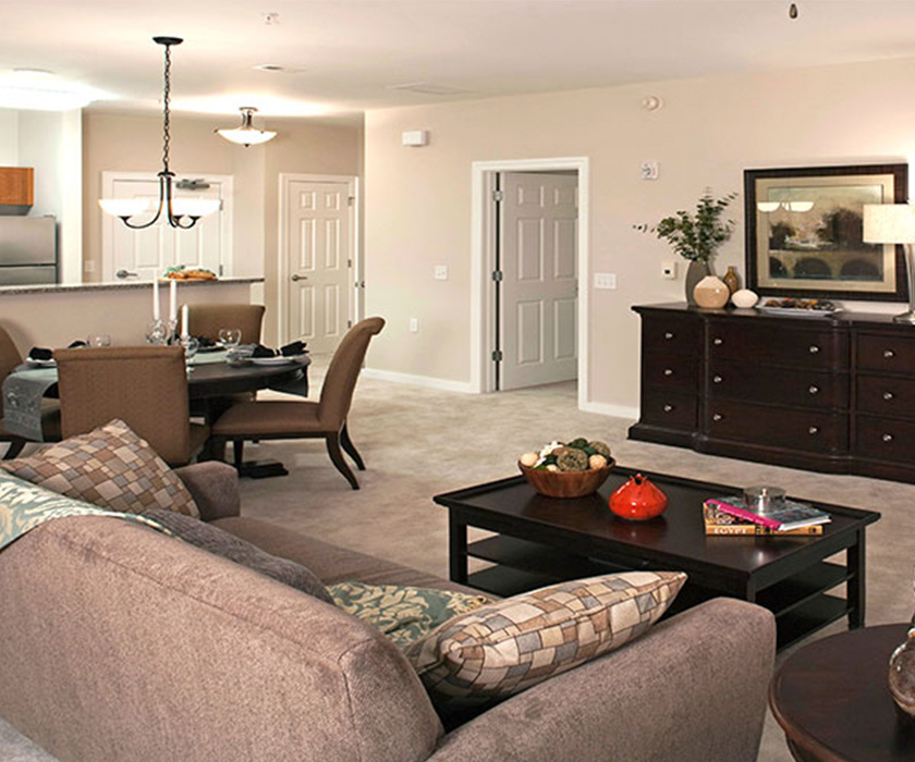Cozy living area with dining table, sofa, and kitchen in a senior living unit.