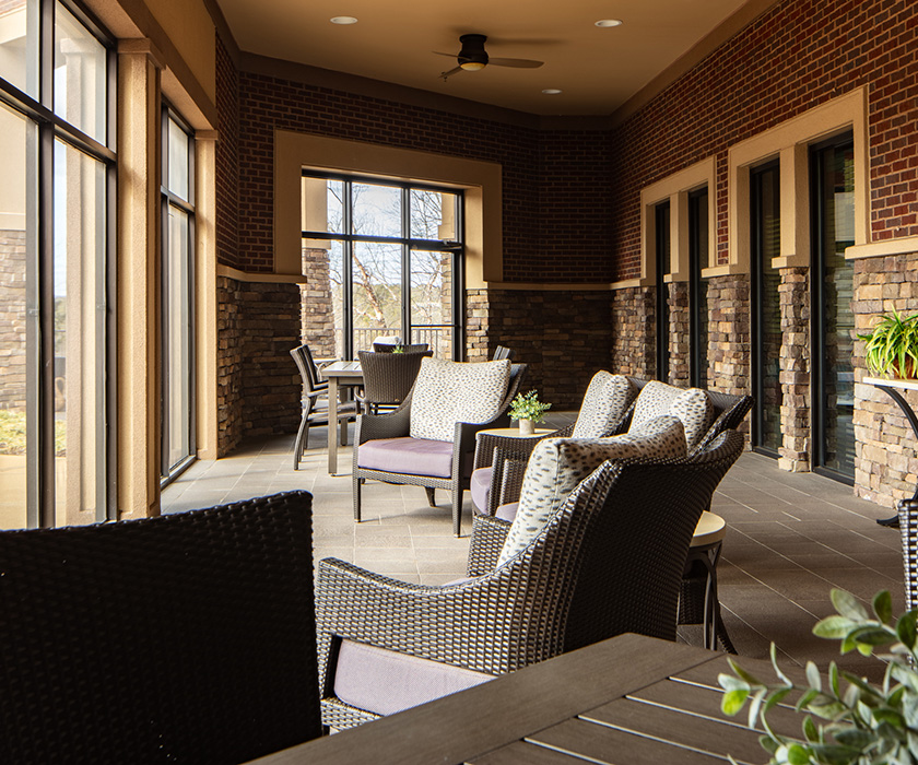 Spacious outdoor seating area with wicker chairs in a senior living community.