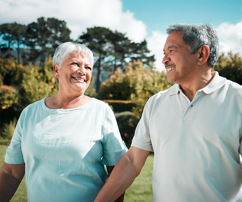 Smiling senior couple enjoying a sunny day outdoors in a garden setting.