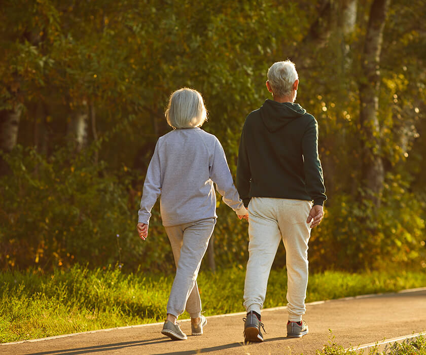 Senior couple holding hands walking down path
