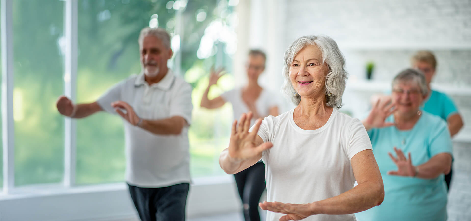 Group of seniors enjoying a tai chi indoors in a bright room.