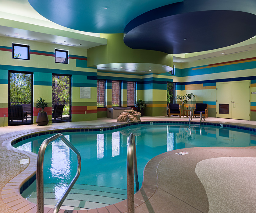 Indoor pool area with colorful walls and seating in a living community.